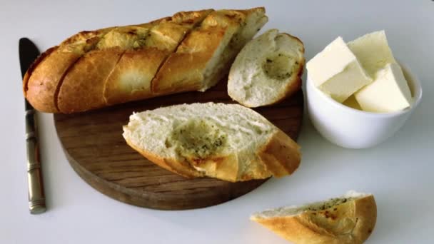 バターの塊と木製のボード上のナイフスライスされた白ニンニクパン — ストック動画