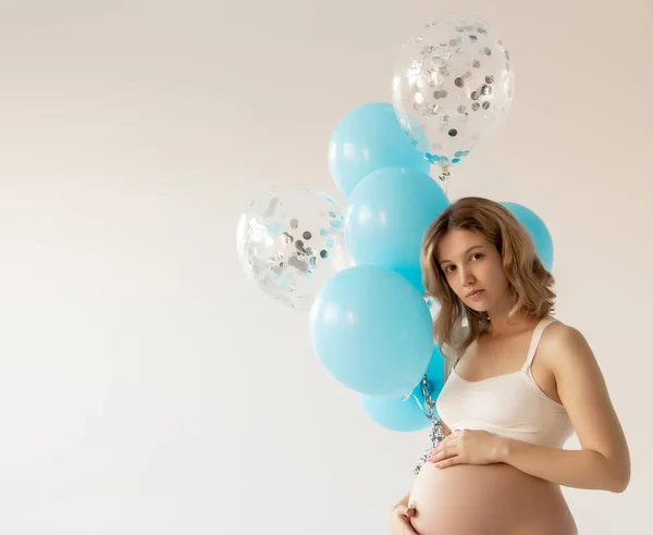 Porträtt av vacker Lycklig gravid kvinna som håller ballonger, tittar på kameran och ler på grå bakgrund. Gravid kvinna med färgglada ballonger. Skönhetstjej. Det är en pojke.. — Stockfoto
