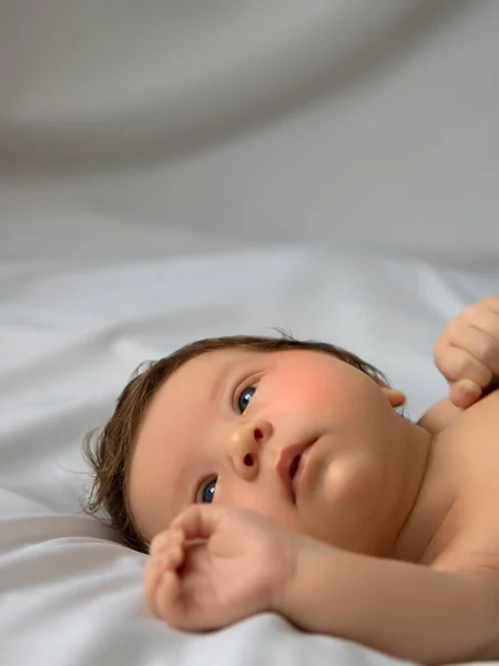Neugeborenes Baby in einem Tuch auf weißer Decke. Schönes Porträt des kleinen Mädchens 7 Tage, eine Woche alt. Baby auf dem Rücken liegend auf weißem Hintergrund — Stockfoto