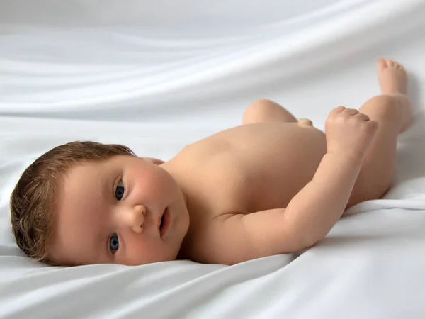 Newborn baby in a wrap on white blanket. Beautiful portrait of little child girl 7 days, one week old. Baby lying on back on white background — Stock Photo, Image