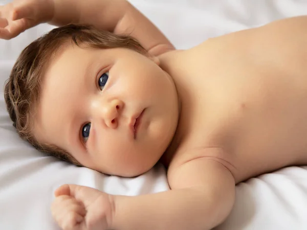 Újszülött baba fehér takaróba csomagolva. Gyönyörű portré egy 7 napos, egy hetes kislányról. Baba feküdt vissza fehér háttér — Stock Fotó