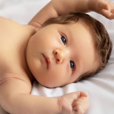 Yeni doğmuş bebeği beyaz battaniyeye sarın. Küçük bir kızın güzel portresi. 7 gün, 1 haftalık. Bebek beyaz arka planda yatıyor