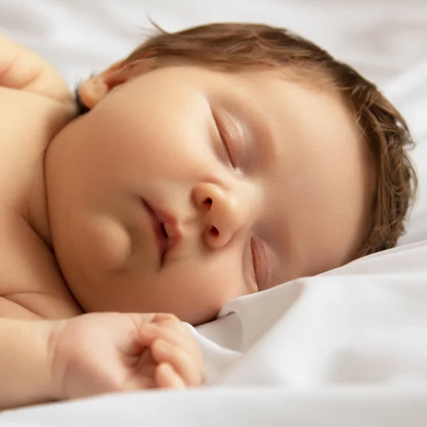 A kislány alszik. Újszülött baba fehér takaróba csomagolva. Gyönyörű portré egy 7 napos, egy hetes kislányról. A baba a hátán fekszik, fehér alapon. Anyaság — Stock Fotó