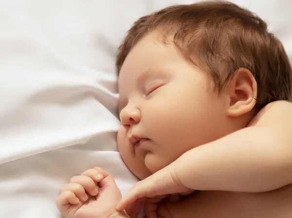 Uma menina com rosto sorridente durante o sono. Pequena menina dormindo em cobertor branco. Belo retrato de menina de 14 dias, duas semanas de idade. Maternidade — Fotografia de Stock