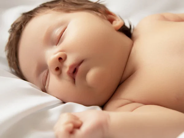 Una niña con la cara sonriente durante el sueño. Niña durmiendo sobre una manta blanca. Hermoso retrato de niña 14 días, dos semanas de edad. Maternidad —  Fotos de Stock