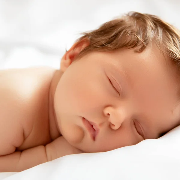 Una bambina con la faccia sorridente durante il sonno. Bambina che dorme su una coperta bianca. Bellissimo ritratto di bambina di 14 giorni, due settimane. Maternità — Foto Stock