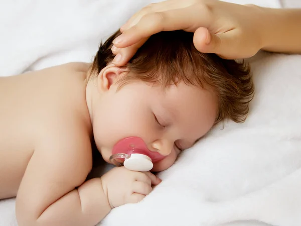 Matka trzymająca głowę dziecka w bezpiecznych rękach. Matki troszczą się. Mamuśki głaskające śpiące niemowlęta podczas dnia śpią w łóżku w domu. Mamusia troszczy się o swoje dziecko podczas gdy on śpi spokojnie — Zdjęcie stockowe