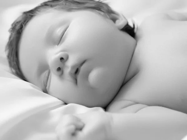 Una niña con la cara sonriente durante el sueño. Niña durmiendo sobre una manta blanca. Hermoso retrato de niña 14 días, dos semanas de edad. Maternidad Fotos De Stock Sin Royalties Gratis