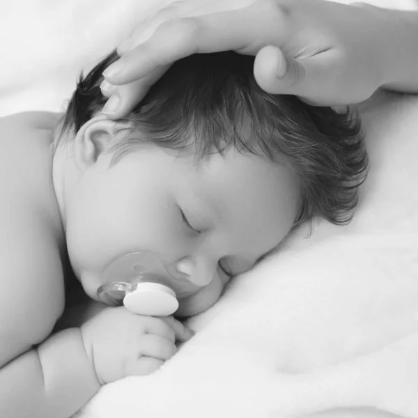 Mãe segurando a cabeça do bebê nas mãos seguras. Cuidado com as mães. Mães mão atordoando dormindo bebê cabeça durante o dia dormir na cama em casa. Mamãe cuidando de seu bebê infantil enquanto ele dorme pacificamente — Fotografia de Stock