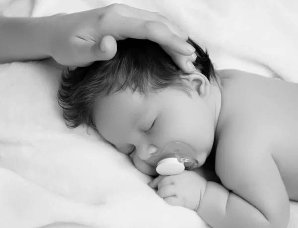 Matka trzymająca głowę dziecka w bezpiecznych rękach. Matki troszczą się. Mamuśki głaskające śpiące niemowlęta podczas dnia śpią w łóżku w domu. Mamusia troszczy się o swoje dziecko podczas gdy on śpi spokojnie — Zdjęcie stockowe