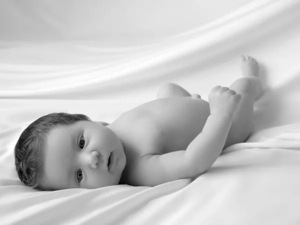 Neugeborenes Baby in einem Tuch auf weißer Decke. Schönes Porträt des kleinen Mädchens 7 Tage, eine Woche alt. Baby auf dem Rücken liegend auf weißem Hintergrund Stockfoto