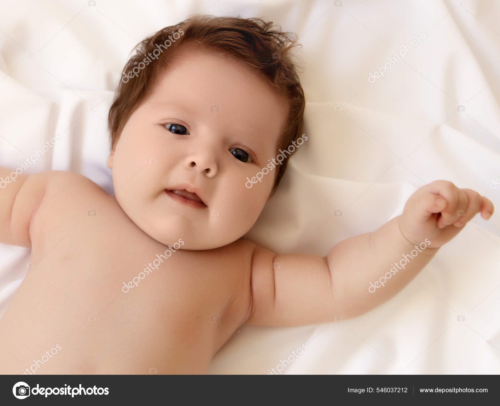 Cute month old Baby girl infant on a bed on her belly with head up