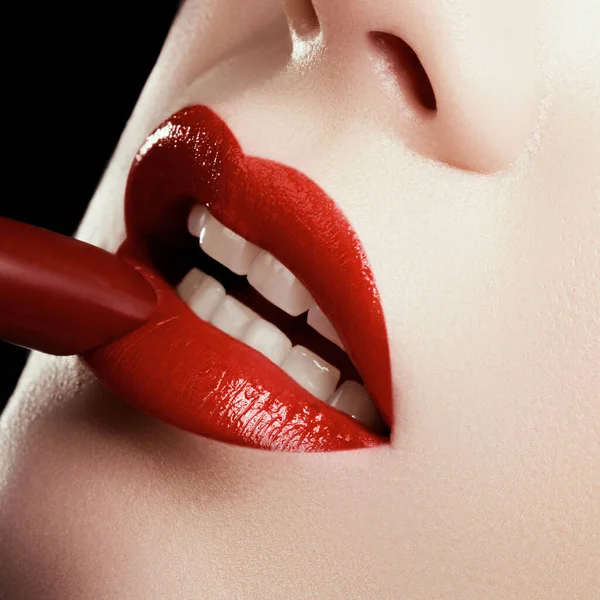 女性嘴唇的特写和时尚的红色妆容。美丽的女性嘴,丰满的嘴唇,完美的妆容.女性脸的一部分。大嘴巴上涂满了美丽的化妆品.选择口红 — 图库照片