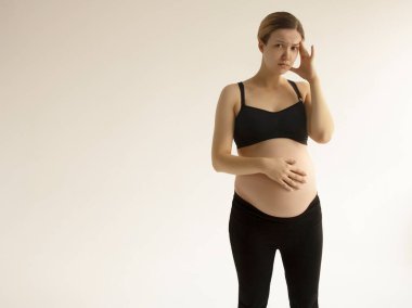 Baş ağrısı ve ağrısı olan hamile bir kadın. Baş ağrısı ve sırt ağrısı olan genç hamile kadın fotokopi alanı. Hamilelik belirtileri, sağlık konsepti