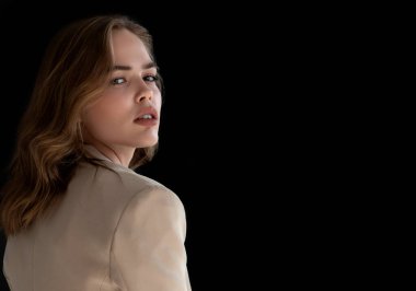 Doğal görünüş. Güzel model kadın. Koyu gri arka planda poz veren genç ve güzel bir manken ile model test portresi. Biege ceketli sarışın kadın. Doğal makyaj.