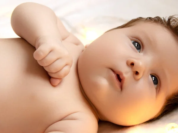 Aranyos lány kis újszülött baba pihentető egy fehér ágy egy takaró meleg puha fények körülöttük. Újszülött baba fehér takaróba csomagolva. Gyönyörű portré a kislányról — Stock Fotó