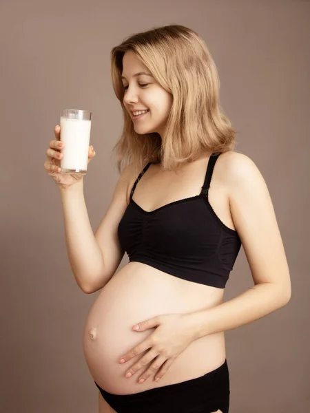 Porträt einer schönen schwangeren Frau mit einem Glas Milch. Frühstück. Das Konzept der sinnvollen Ernährung schwanger. Seitenansicht. Schwangere trinkt Milch Stockfoto