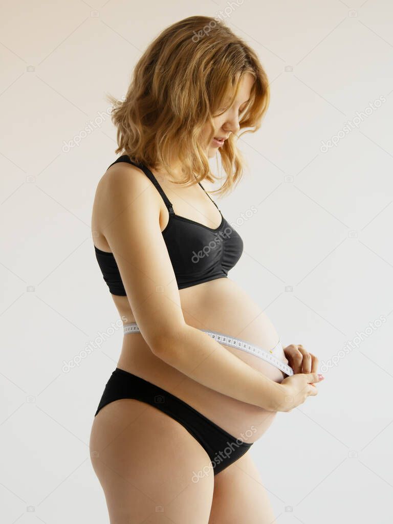 Fotos de Hermosa mujer embarazada con ropa para mujeres embarazadas está  midiendo su barriga desnuda, sonriendo, sobre un fondo blanco. Mujer  embarazada sonriente midiendo su gran vientre - Imagen de ©  looking_2_the_sky #547489474