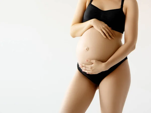 Жінка стоїть і торкається її голий великий живіт. Ізольовані на сірому фоні. Емоційний час люблячої вагітності - 37 тижнів. Дитячі очікування. Концепція любові, щастя та безпеки. крупним планом — стокове фото