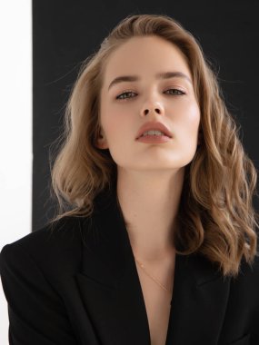 Doğal görünüş. Güzel model kadın. Gri arka planda poz veren genç ve güzel bir model ile model test portresi. Siyah ceketli sarışın bir kadın. Doğal makyaj.