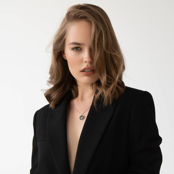 Естественный вид. Красотка-модель. Образец тестового портрета с молодой красивой моделью, позирующей на сером фоне. Блондинка в черном пиджаке. Макияж