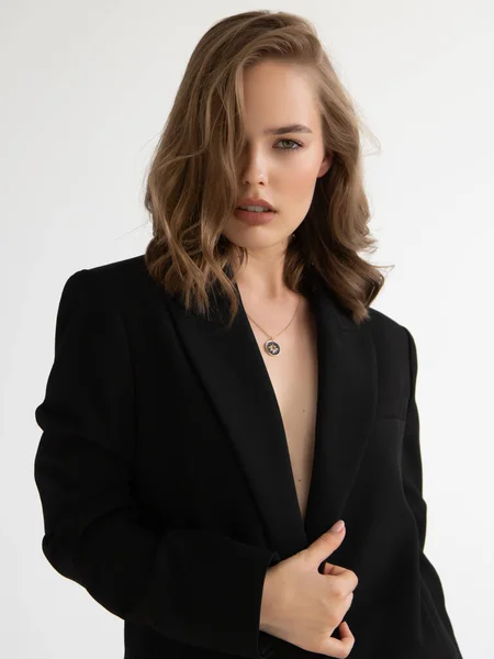 Natürliches Aussehen. Schönheit Modell Frau. Modeltest Porträt mit jungen schönen Mode-Modell posiert auf grauem Hintergrund. Blonde Frau im schwarzen Blazer. Natürliches Make-up Stockbild