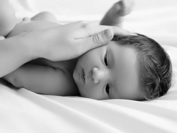 Mutter hält Kopf des Babys in sicheren Händen Mütter kümmern sich. Mütter streicheln schlafende Babys tagsüber im Bett zu Hause. Mama kümmert sich um ihr Baby, während er friedlich schläft — Stockfoto