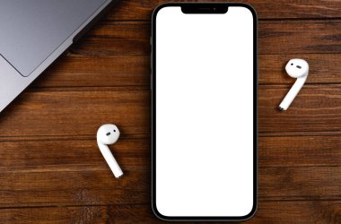 mockup smartphone iPhone 12 Pro Max with blank white screen, AirPods on wood background top view. Apple is a multinational technology company. Moscow, Russia - June 20, 2021