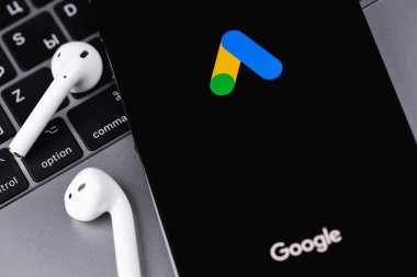 Google Ads (AdWords) logo mobile app on dark screen smartphone iPhone with Macbook, AirPods. Google Ads is a contextual service, mainly search advertising. Moscow, Russia -  July 21, 2021