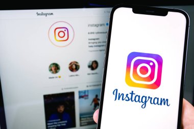 Instagram logo mobile app on screen smartphone iPhone with notebook Macbook. Instagram is a photo-sharing app for smartphones. Moscow, Russia - July 22, 2021