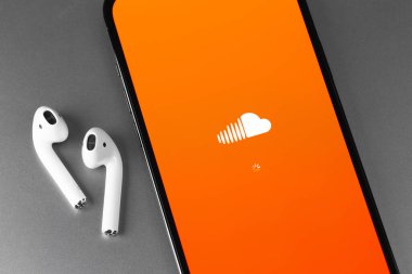 Soundcloud logo mobile app on screen smartphone iPhone and AirPods closeup. SoundCloud is a global online audio distribution platform. Moscow, Russia - June 10, 2021