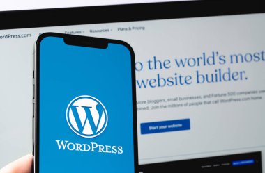 WordPress logo mobile app on screen smartphone iPhone with Macbook display closeup. WordPress - open source site content management system. Moscow, Russia - June 22, 2021
