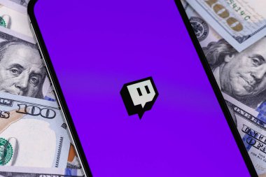 Twitch logo on screen smartphone iPhone with dollars, money closeup. Twitch is a video streaming service specializing in computer games. Moscow, Russia - September 27, 2021