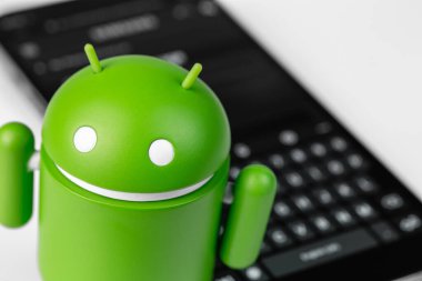 Google Android figure and smartphone with keyboard closeup. Google Android is the operating system for smartphones, tablet computers, e-books and other devices. Moscow, Russia - September 10, 2021