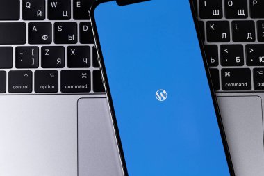 WordPress logo mobile app on screen smartphone iPhone with Macbook keyboard closeup. WordPress - open source site content management system. Moscow, Russia - January 17, 2022