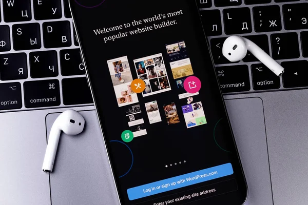 WordPress logo mobile app on screen smartphone iPhone with AirPods, Macbook closeup. WordPress - open source site content management system. Moscow, Russia - January 17, 2022