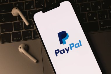 PayPal logo mobile app on screen smartphone iPhone and AirPods, Macbook keyboard closeup. Paypal is an internet based digital money transfer service. Batumi, Georgia - March 4, 2022
