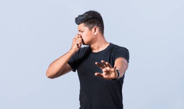 Kafası karışmış mutsuz bir adam burnu parmaklarıyla kavrıyor ve elini uzatıyor tiksinti duyuyor, burnunu bir hoşnutsuzluk hareketiyle kapatıyor.