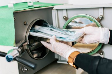 Aletlerini sterilize eden bir diş hekimi, diş sterilizatörü olan bir diş hekimi, buhar sterilizatörüyle dişçiyi kapatan bir diş hekimi.