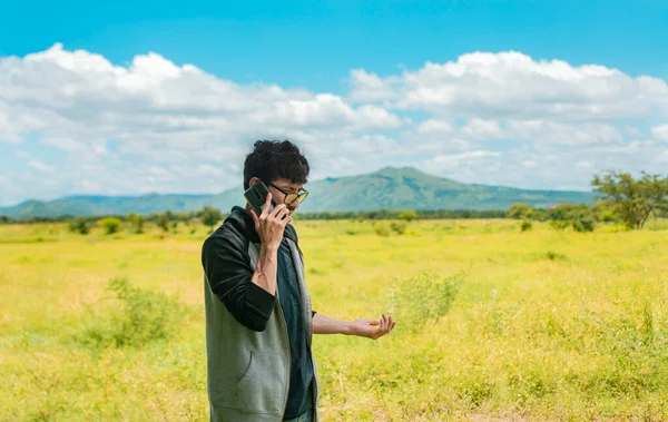 Man calling on the phone in the field, A man in a beautiful field talking on the phone, person with cell phone calling on the phone in the field, people talking on the cell phone in the field