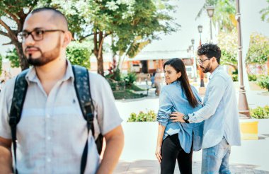 Unfaithful girlfriend looking at another man on the street, Unfaithful girl looking at another man on street while her boyfriend claims her. Disloyal girlfriend looking at another guy on the street.