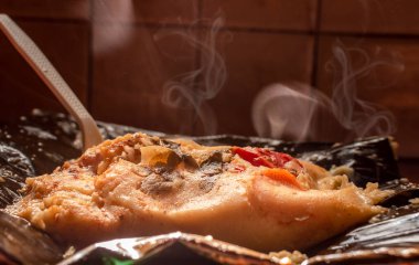 A freshly served traditional Nacatamal. Side view of Traditional Nacatamal served on banana leaf, Close-up of Nicaraguan Nacatamal ready to eat, Homemade Nacatamal served in a banana leaf