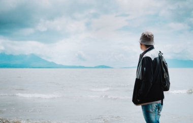 Volkanları olan bir göle bakan turistin dikiz görüntüsü. Güneşli bir günde göle bakan bir kaşif. Arkadan şapkalı turist Rivas, Nikaragua 'da volkanları olan bir göle bakıyor.