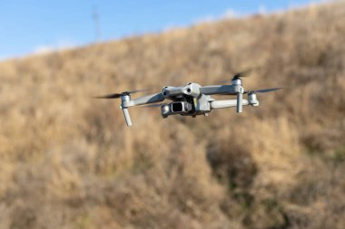 Havada uçan küçük bir dronun yakın çekim görüntüsü. Metin için yer.