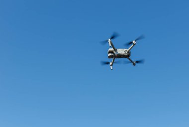 Havada uçan küçük bir dronun alttaki görüntüsü. Metin için yer.