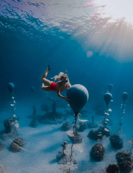 Femme plongeuse libre en maillot de bain rouge, sous l'eau avec des rayons de soleil étonnants et des statues. Plongée sous-marine dans l'océan — Photo