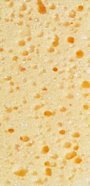 Parlak bir yüzeyde farklı boyutlarda yuvarlak oyuklar olan soyut sarı arka plan. Dikey fotoğrafçılık