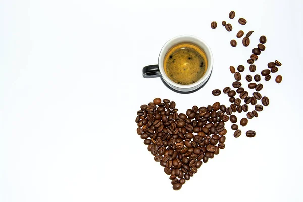 Een kopje espresso met schuim naast koffiebonen in de vorm van een hartje. Lifestyle. Je eigen ruimte. Vlak leggen. Copispace. — Stockfoto