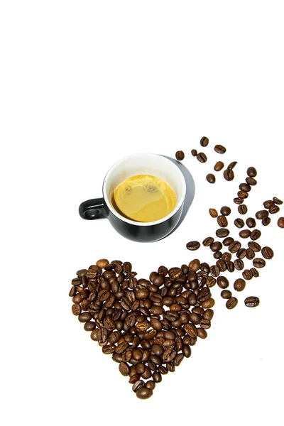 Kleine zwarte hartvormige koffiekop met verspreide bonen op een witte achtergrond. Vooraanzicht. Isoleer. Levensstijl. — Stockfoto