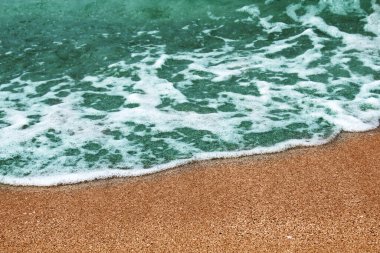 Çakıl taşlı sahilde mavi deniz dalgası.